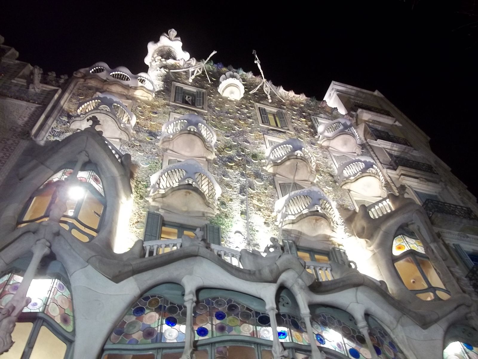 Fachada da Casa Batlló iluminada à noite, com balcões em forma de máscara