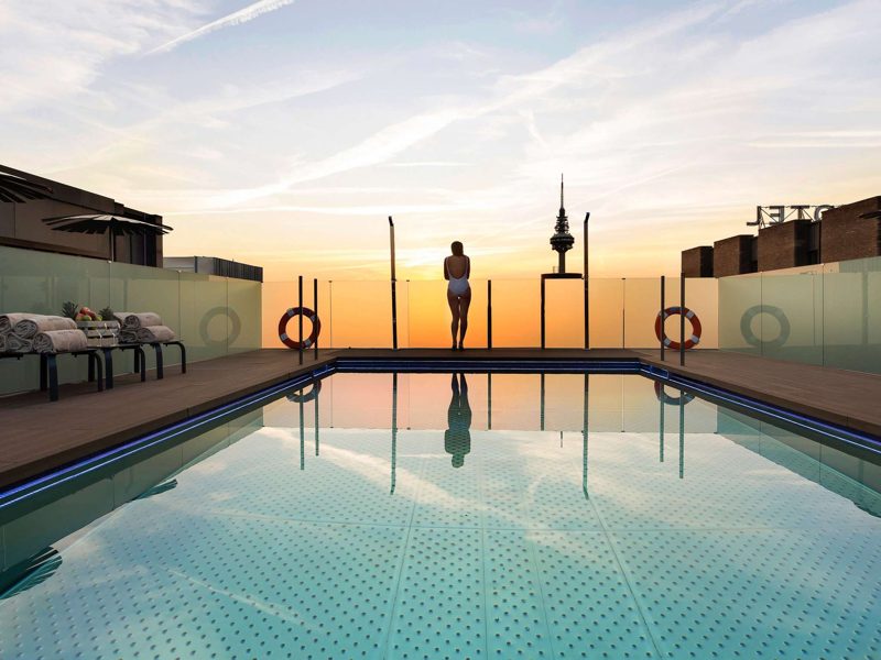 Piscina na cobertura do hotel ao pôr do sol, com a torre de comunicações de Madri ao fundo